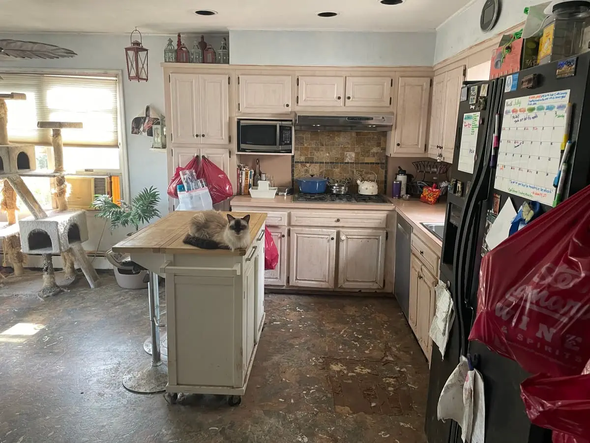 Selling with a non-paying tenant in Massapequa: kitchen with worn floors and an island cart