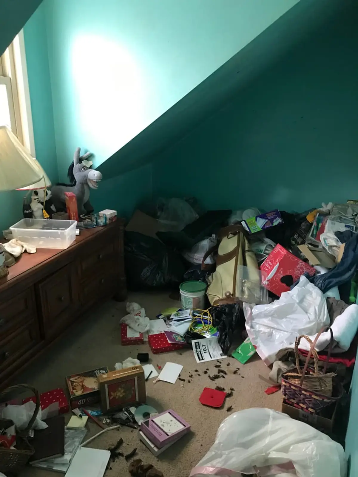 Selling a hoarder house in Massapequa: teal attic bedroom buried in bags and belongings