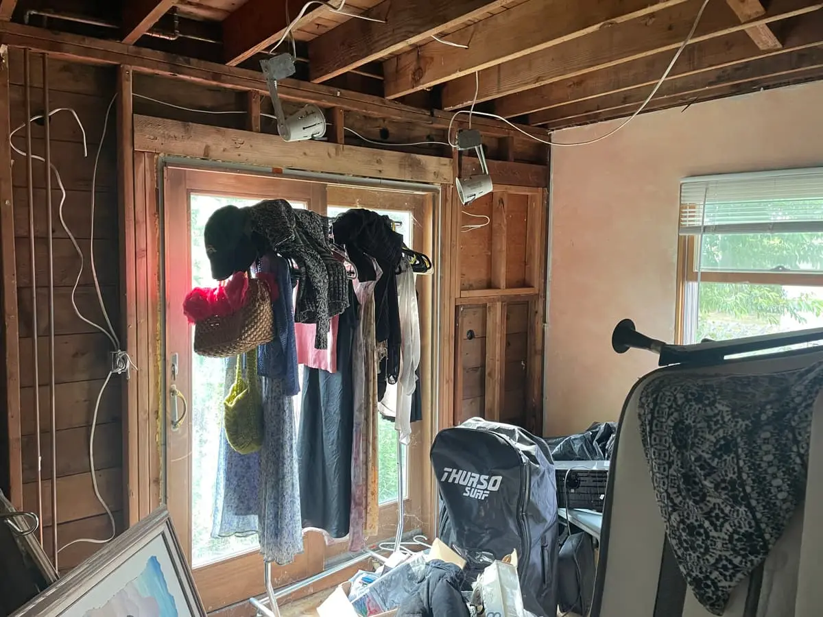 Selling a fire-damaged house in Massapequa: wall opened to the studs behind hanging clothes